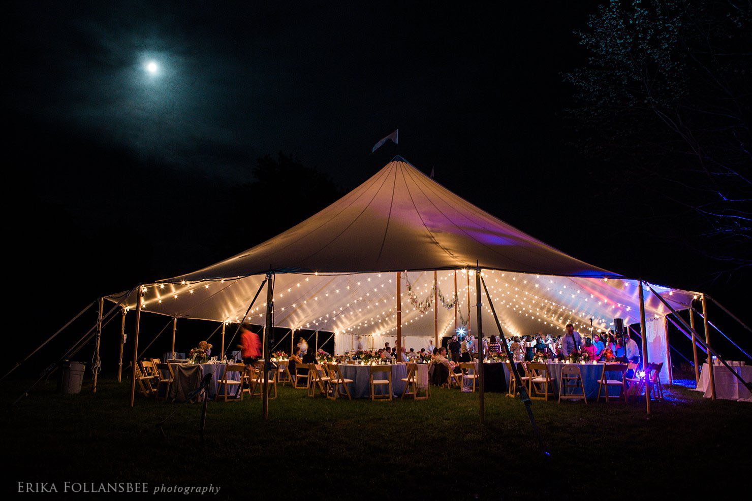 Night photo of the tent lit up by bistro lights