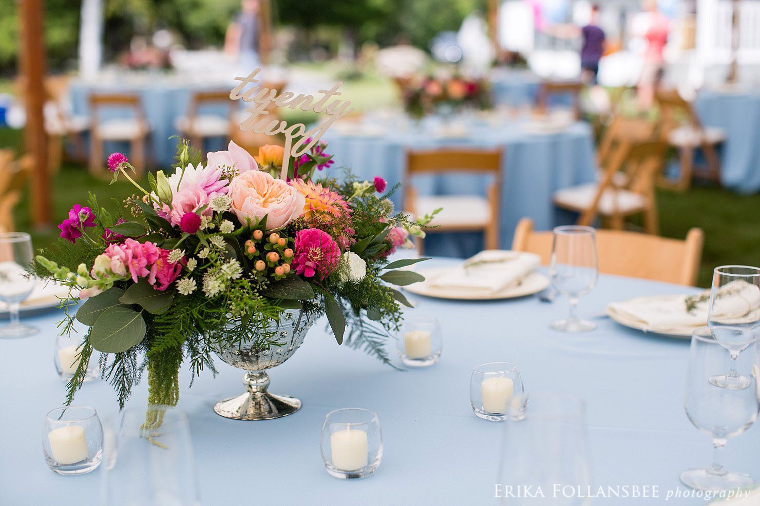 Colorful centerpieces by Sorella Flower Company on blue tablecloths with mismatched china plates
